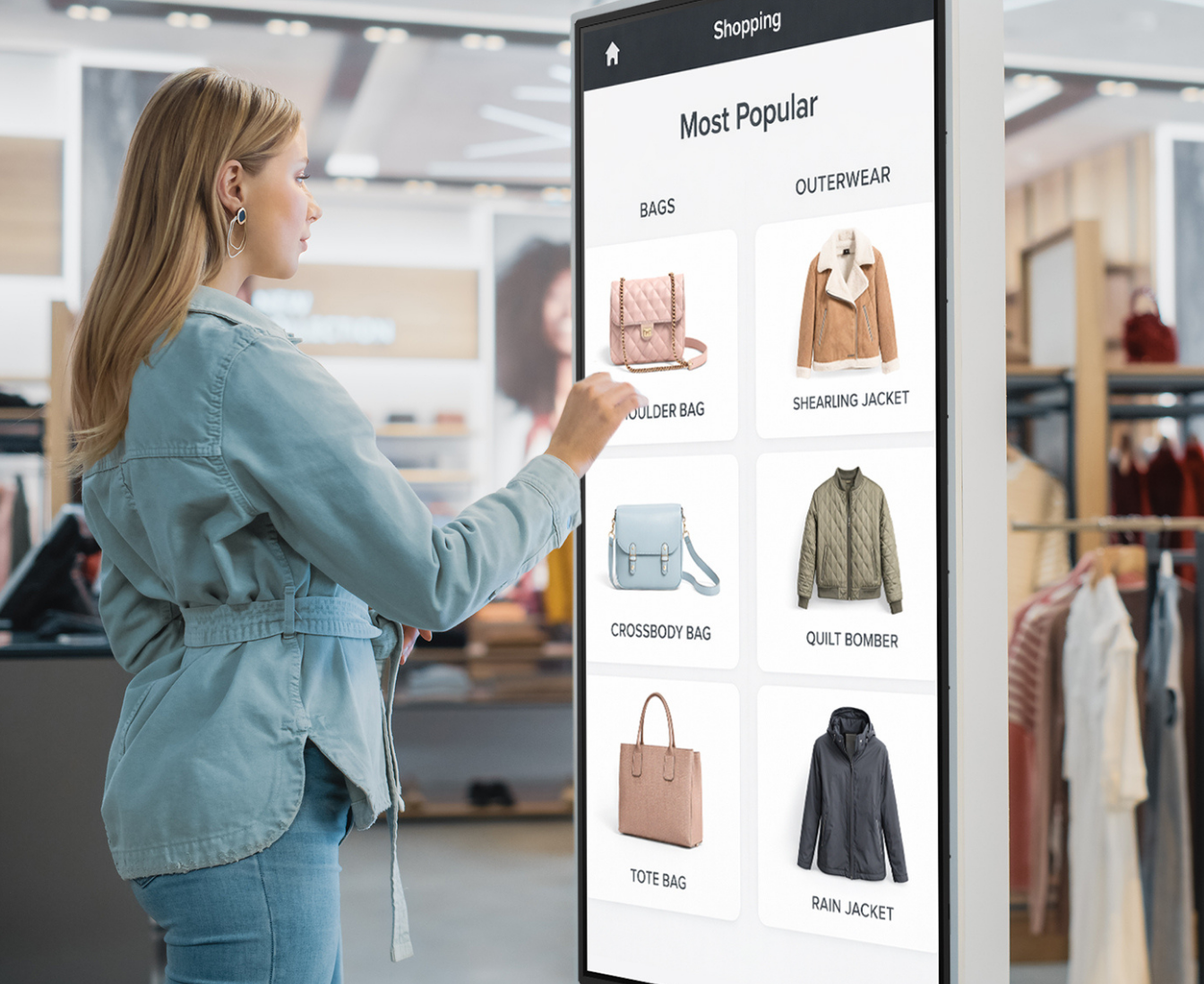person with long hair using the touch screen looking up purses in a retail setting